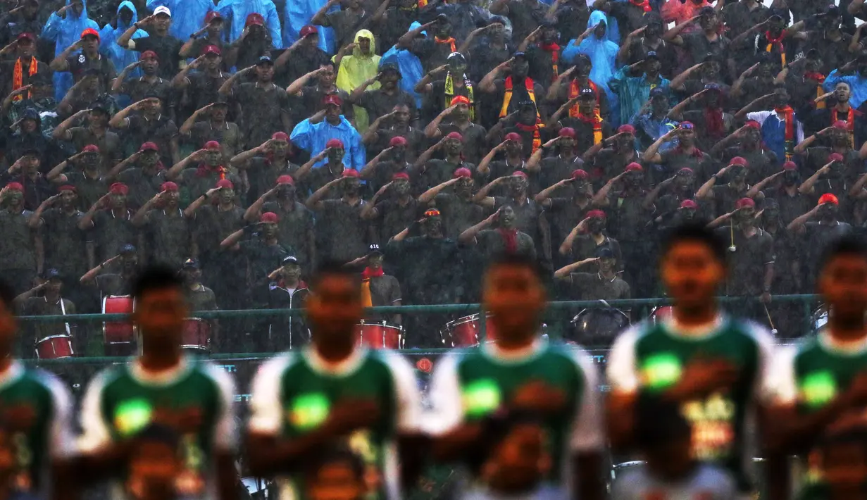 Suporter PS TNI melakukan penghormatan saat menyanyikan lagu Indonesia Raya bersama pemain PS TNI pada laga Piala Jenderal Sudirman di Stadion Manahan, Solo, Sabtu (12/11/2015). (Bola.com/Nicklas Hanoatubun)