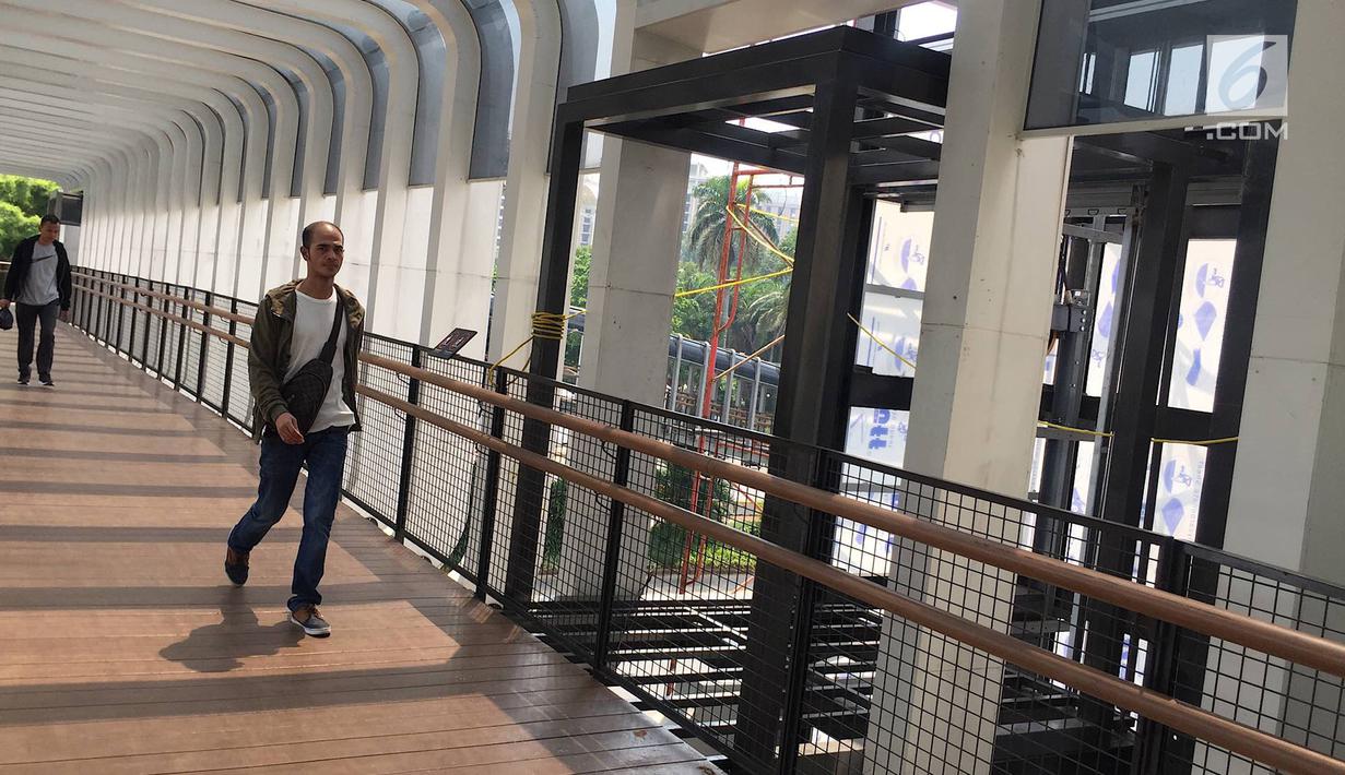 Pejalan kaki melintas di dekat pembangunan lift pada jembatan penyeberangan orang di Jakarta, Senin (13/5). Pembangunan lift pada tiga JPO yang berada di Jalan Sudirman itu bertujuan meningkatkan kenyamanan kepada warga dan ditargetkan rampung akhir bulan ini.(Liputan6.com/Immanuel Antonius)