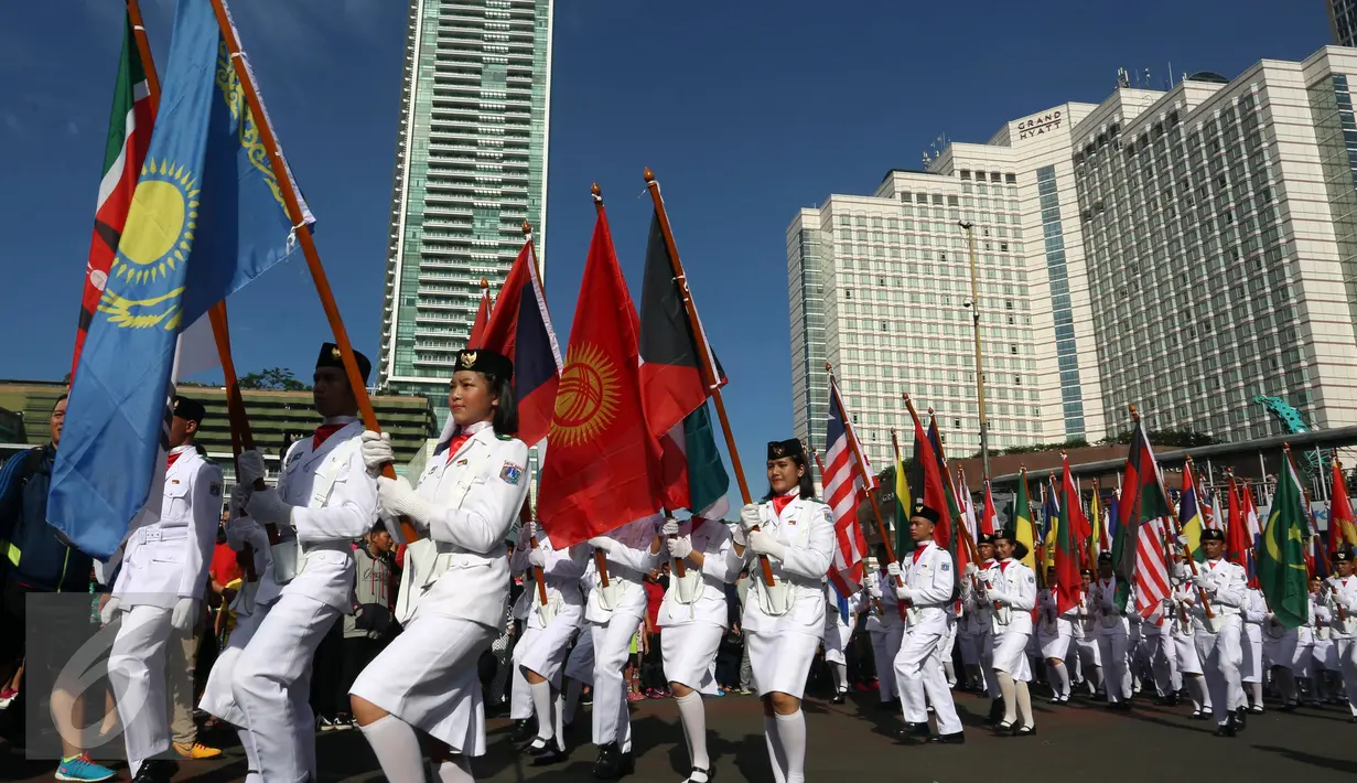 Sejumlah anggota Paskib membawa bendera peserta Sidang Umum Interpol Ke-85 di kawasan Bundaran HI, Jakarta, Minggu (30/10).  (Liputan6.com/Johan Tallo)