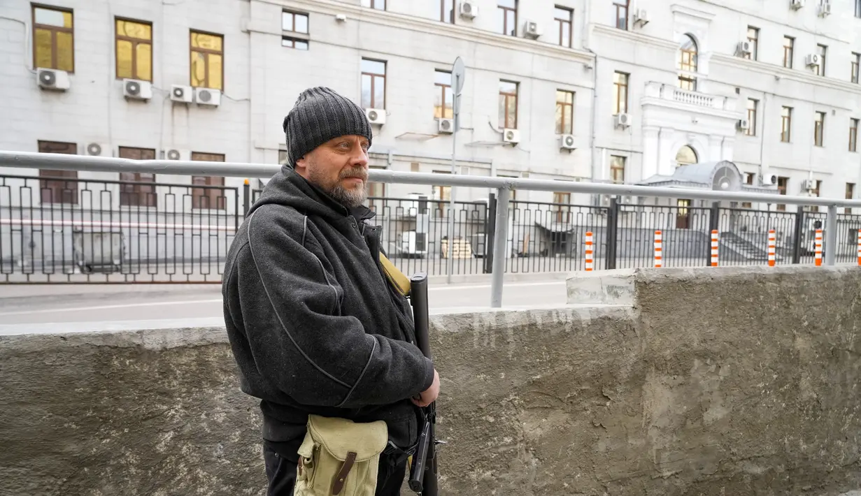 Seorang pria pertahanan sipil bersenjata berpatroli di jalan yang kosong karena jam malam di Kyiv, Ukraina, Minggu (27/2/2022). Pihak berwenang Ukraina mengatakan bahwa pasukan Rusia telah memasuki kota terbesar kedua di Ukraina Kharkiv dan pertempuran di jalan-jalan. (AP Photo/Efrem Lukatsky)