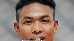 Sprinter Indonesia, Lalu Muhammad Zohri menggigit medali usai mengikuti kategori 100 meter dalam Kejuaraan Atletik Asia di Doha, Qatar, Senin (22/4). Zohri merebut medali perak dengan catatan waktu 10,13 detik yang juga memecahkan rekor pelari tercepat Asia Tenggara, Suryo Agung. (AP/Vincent Thian)