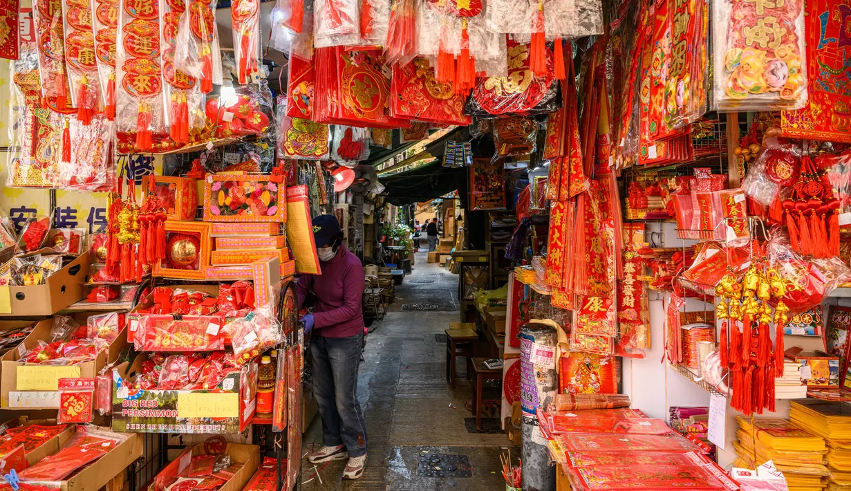 Seorang vendor menunggu pelanggan di kiosnya yang menjual dekorasi di Hong Kong (15/1/2021). Menjelang Tahun Baru Imlek, tahun ini menandai Tahun Sapi, yang jatuh pada 12 Februari. (AFP/Anthony Wallace)