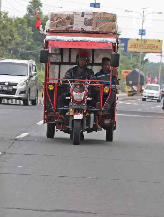 Pemudik bersama keluarganya menggunakan motor bak roda tiga saat perjalanan mudik melintasi Jalur Pantura kawasan Pemalang, Jawa Tengah, Senin (3/6/2019). Keluarga ini sudah sejak tiga tahun lalu menggunakan motor bak roda tiga untuk mudik. (Liputan6.com/Herman Zakharia)