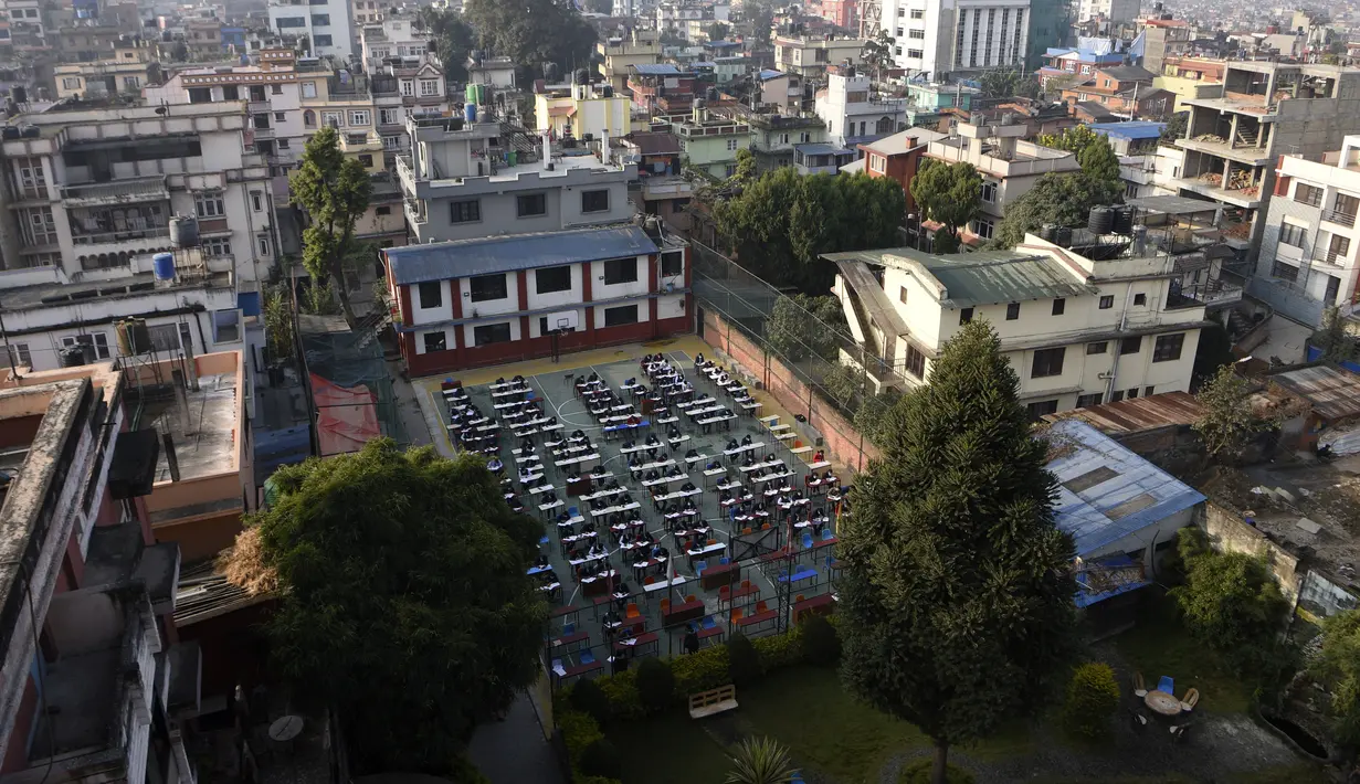 Siswa yang mengenakan masker mengikuti ujian kenaikan kelas XII di lapangan sekolah di Kathmandu, Nepal, Senin (23/11/2020). Nasib sekitar 450.000 siswa kelas XII digantung akibat COVID-19 saat ujian yang dijadwalkan mulai 20 April ditunda karena lockdown pada 24 Maret lalu. (PRAKASH MATHEMA/AFP)