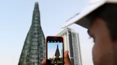 Seorang pria Sri Lanka mengambil foto pohon Natal di Kolombo, Sabtu (24/12). Tingginya yang mencapai 50 meter ini dinobatkan sebagai pohon natal tertinggi di dunia. (AFP PHOTO / Lakruwan Wanniarachchi)