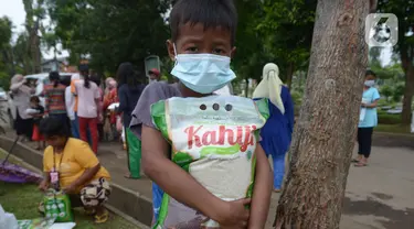 Seorang anak membawa beras seusai pembagian sembako di TPU Malaka, Pondok Kopi, Jakarta, Jumat (4/3/2022). Pembagian sejumlah sembako secara gratis yang diperuntukan bagi kaum duafa ini berupa beras dan minyak goreng. (merdeka.com/Imam Buhori)