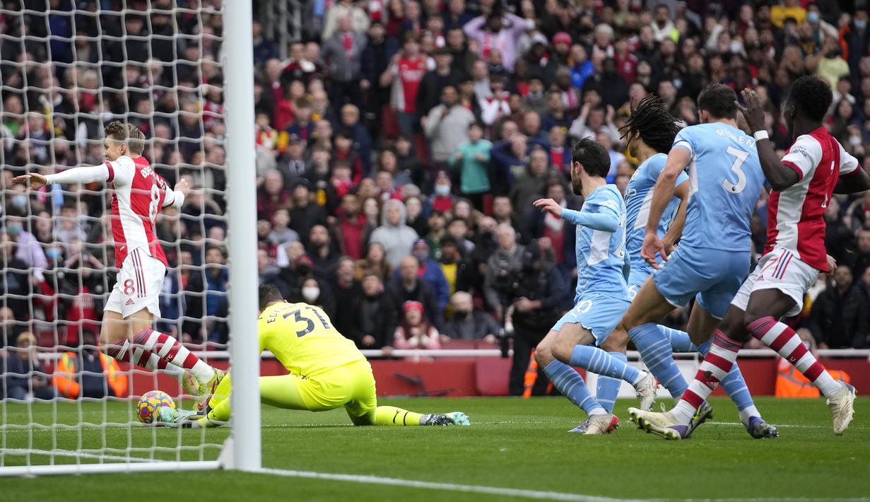 Pada menit ke-10 Arsenal nyaris memperoleh tendangan penalti. Martin Odegaard sekilas tampak dijatuhkan oleh kiper Manchester City Ederson di dalam kotak penalti. Usai memeriksa VAR, Ederson dinilai menyentuh bola terlebih dahulu. (AP/Matt Dunham)