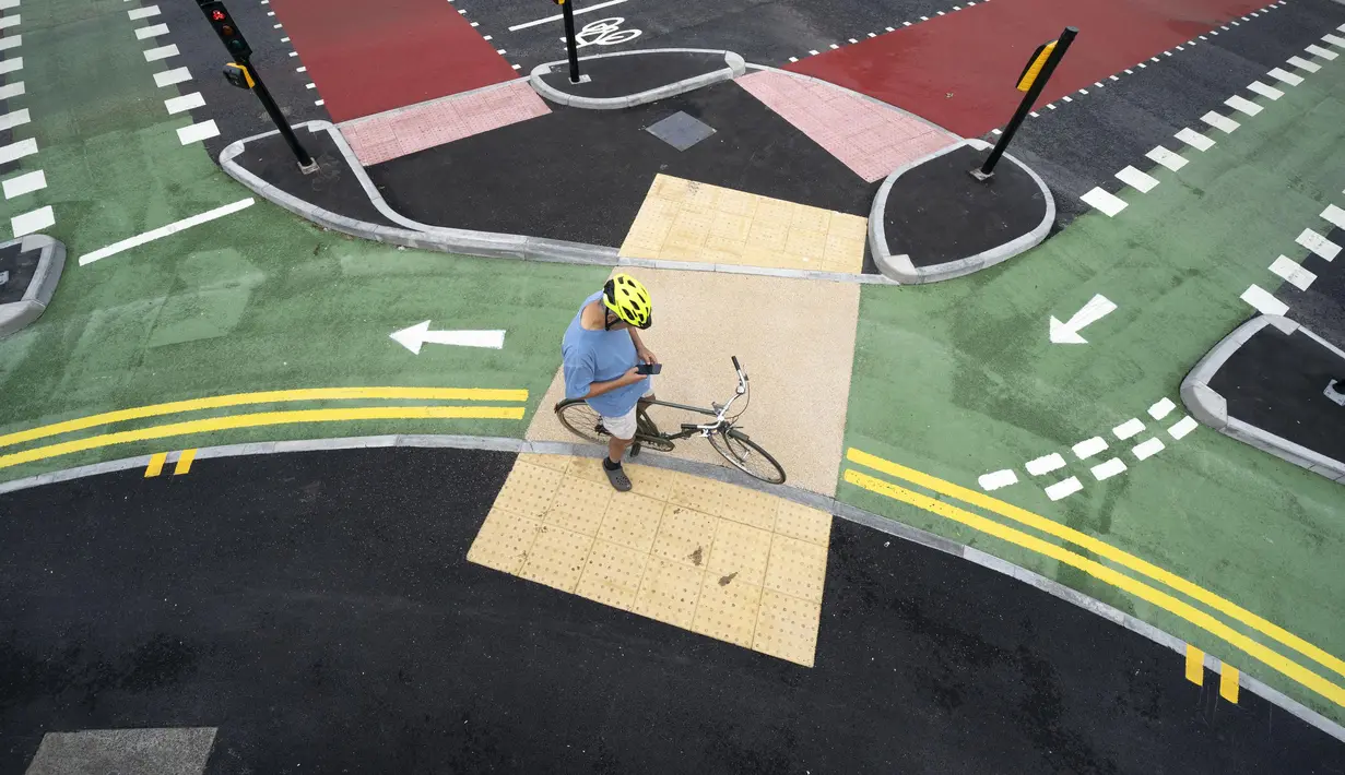 Seorang pesepeda menunggu pergantian lampu lalu lintas di jalur sepeda persimpangan CYCLOPS (Cycle Optimized Protected Signals) di wilayah selatan Manchester, Inggris (9/7/2020). Persimpangan CYCLOPS ini dibuat untuk mengurangi kemungkinan terjadinya tabrakan atau konflik. (Xinhua/Jon Super)