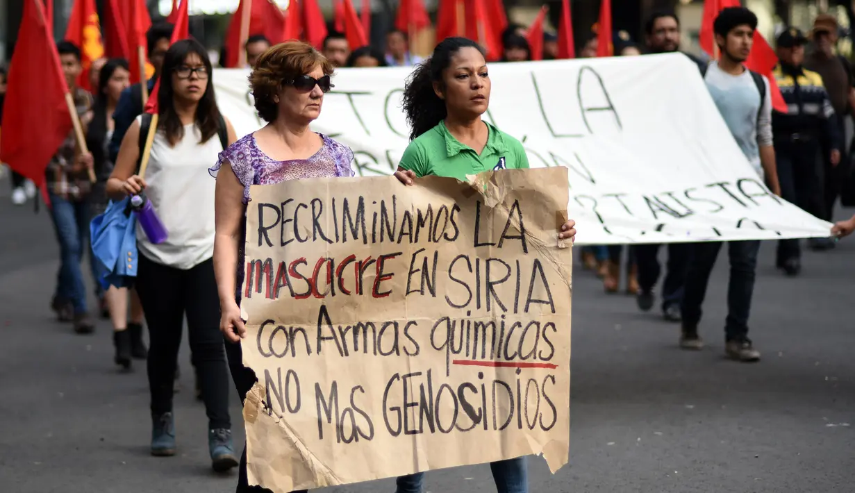 Demonstran membawa tulisan saat menggelar aksi di depan Kedubes AS di Mexico City, Minggu (9/4). Mereka mengecam serangan bom kimia yang telah menewaskan warga Suriah dan menolak intervensi AS. (AFP PHOTO / Pedro Pardo)