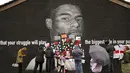 Orang-orang menempatkan pesan dukungan di atas bin liner yang ditempel di atas kata-kata ofensif di mural striker Inggris Marcus Rashford di dinding Coffee House Cafe, yang dirusak pagi hari setelah Inggris kalah di final Euro 2021 melawan Italia, di Manchester (12/7/2021). (Peter Byrne/PA via AP)
