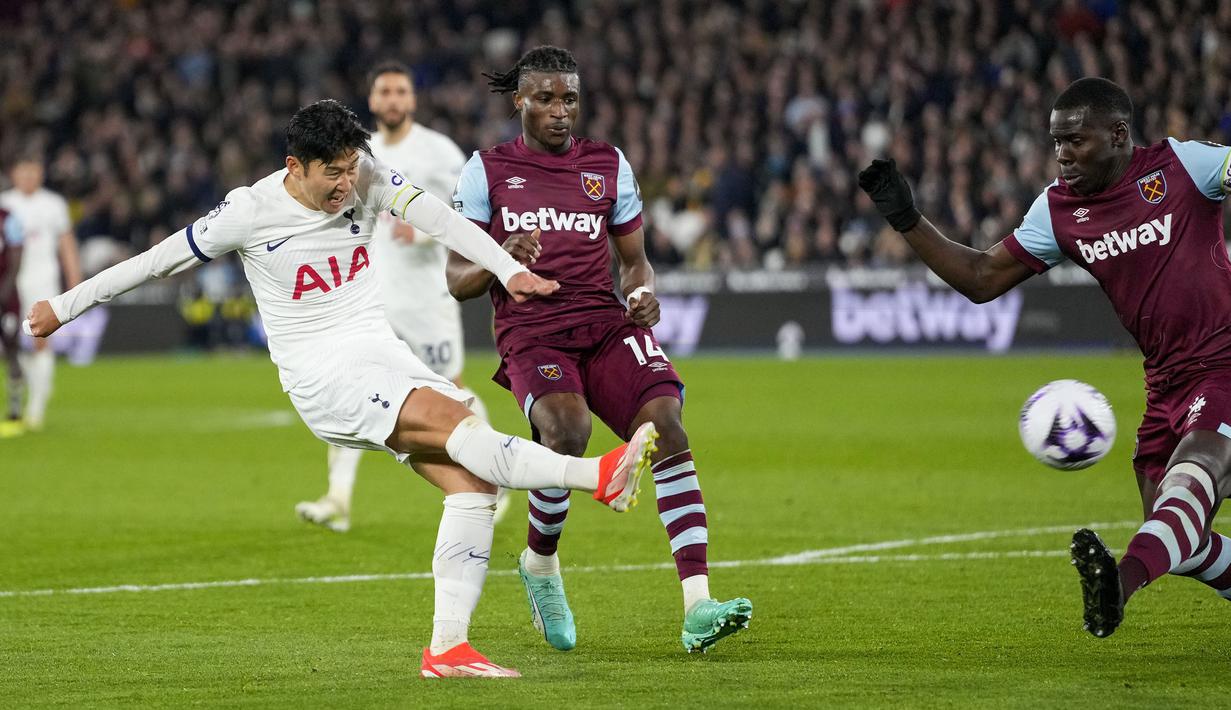 Striker Tottenham Hotspur, Son Heung-min (kiri) melepaskan tendangan yang berusaha diblok bek West Ham United, Kurt Zouma pada laga pekan ke-31 Premier League 2023/2024 di London Stadium, London, Selasa (2/4/2024) malam. (AP Photo/Kirsty Wigglesworth)