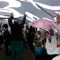 Sejumlah peserta aksi 299 berteduh di bawah bendera putih berlafazkan tauhid saat berkumpul di depan MPR/DPR, Senayan, Jakarta, Jumat (29/9). Aksi  ini diikuti berbagai elemen masyarakat dari Jabodetabek maupun dari luar daerah. (Liputan6.com/JohanTallo)