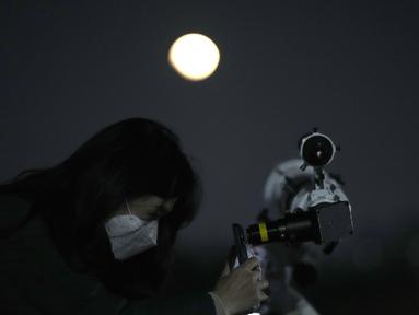 Seorang wanita mengambil foto bulan melalui teleskop saat gerhana bulan di Goyang, Korea Selatan, Selasa, 8 November 2022. Fenomena gerhana bulan total terjadi pada 8 November 2022 di berbagai negara. (AP Photo/Lee Jin-man)