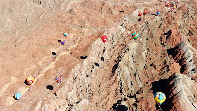 Sejumlah balon udara terbang di atas Taman Geologi Nasional Danxia di Zhangye, Provinsi Gansu, China barat laut, pada 26 Juli 2020. Sebuah festival balon udara internasional dibuka di Zhangye pada Minggu (26/7). Total 100 balon udara akan ditampilkan dalam festival tersebut. (Xinhua/Cheng Lin)