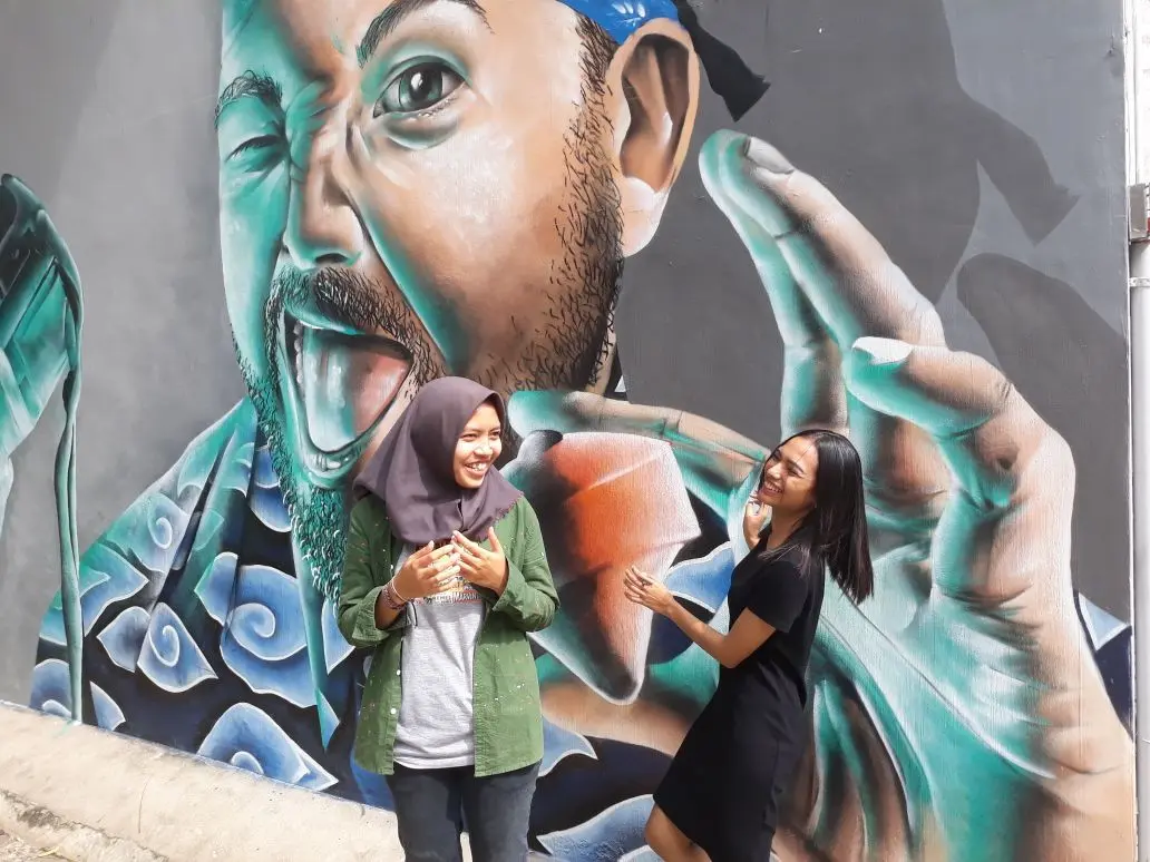 Dua seniman Indonesia Bunga dan Kare (kiri) berpose di depan mural karya mereka.
