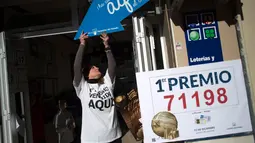 Seorang wanita bersiap merayakan kemenangan undian lotre di di sebuah toko di Malaga, Spanyol (22/12). Lotre Natal tahunan tersebut bernilai total lebih dari 10 juta euro atau lebih dari Rp 160 miliar. (AFP Photo/Jorge Guerrero)