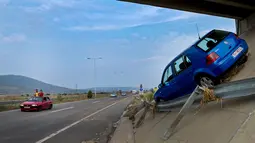 Sebuah mobil terdampar di atas ringroad akibat banjir bandang di Ibu Kota Skopje, Makedonia, Minggu (7/8). Pemerintah menyatakan keadaan darurat sehari setelah setidaknya 21 orang tewas dalam banjir bandang yang disebabkan badai. (Robert ATANASOVSKI/AFP)