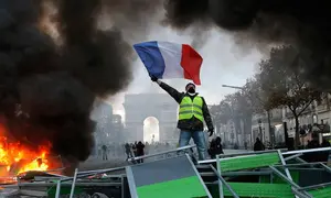 Demonstran mengibarkan bendera Prancis saat kerusuhan menentang kenaikan harga bahan bakar di Paris, Prancis, Sabtu (24/11). Demonstrasi terjadi oleh dorongan gerakan "rompi kuning". (AP Photo/Michel Euler)