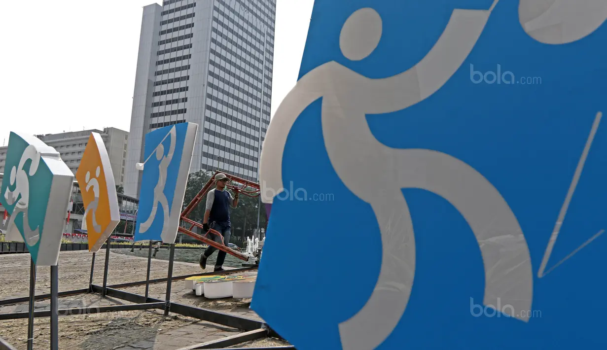 Pekerja mengangkut besi saat merampungkan pengerjaan logo Asian Games 2018 di Bundaran HI, Jakarta, (17/8/2017), Asian Games mengambil tema Energy Of Asia dan akan dibuka oleh Presiden Republik Indonesia Joko Widodo. (Bola.com/Nicklas Hanoatubun)
