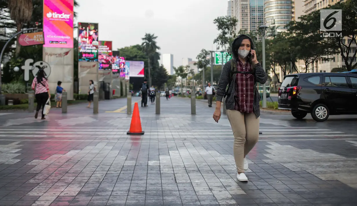 Seorang wanita berjalan mengenakan masker pelindung untuk menghindari polusi udara buruk di Jakarta, Rabu (17/7/2019). Dinkes DKI menyarankan masyarakat untuk menggunakan masker saat beraktivitas untuk mencegah dampak polusi udara pada tubuh. (Liputan6.com/Faizal Fanani)
