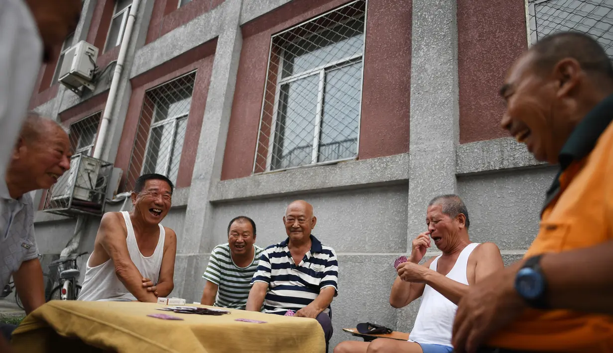 Sekelompok pria tertawa saat bermain kartu remi di trotoar di luar gedung apartemen di Beijing, China (10/8). Ada 1001 macam permainan kartu. Setiap negara, bahkan wilayah suatu negara, memiliki jenis permainannya sendiri. (AFP Photo/Greg Baker)