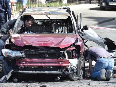 Polisi Ukraina memeriksa bangkai mobil yang ditumpangi jurnalis investigasi ternama, Pavel Sheremet, yang tewas di Kiev, Rabu (20/7). Jurnalis Ukrayina Pravda itu sedang mengendarai mobil ke tempat kerja ketika mobil tersebut meledak (Sergei SUPINSKY/AFP)