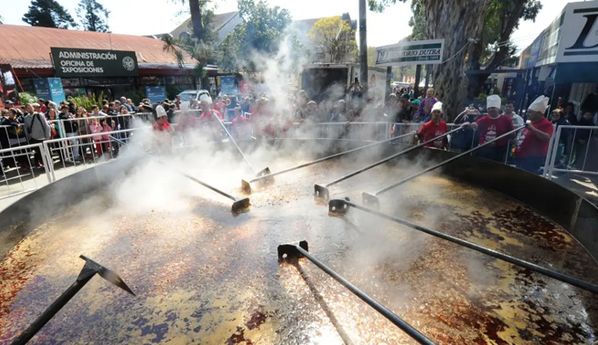 Para koki mempersiapkan kacang lentil rebus di panci raksasa untuk memecahkan rekor dunia Guinness Record dalam acara Prado Rural di Montevideo, Uruguay, Minggu (13/9/2015). Kacang tersebut cukup untuk memberi makan 10.000 orang. (AFP PHOTO/Miguel Rojo)