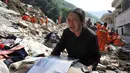 Seorang wanita menangis sambil memegangi album di atas puing-puing rumahnya yang hancur akibat gempa di Longtoushan, provinsi Yunan, Tiongkok, (6/8/2014). (REUTERS/Stringer)
