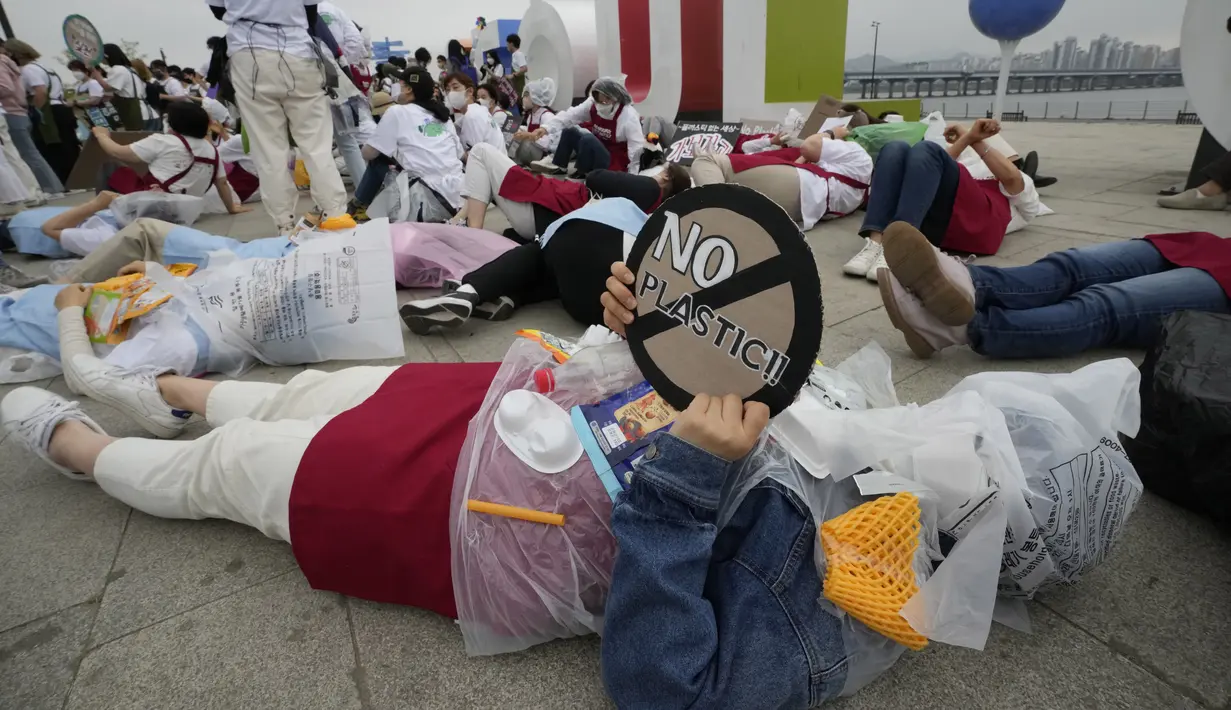 <p>Aktivis lingkungan mengenakan pakaian yang terbuat dari sampah plastik berbaring di tanah selama kampanye untuk memperingati Hari Bumi melawan perubahan iklim di Seoul, Korea Selatan, Jumat (22/4/2022). (AP Photo/Ahn Young-joon)</p>