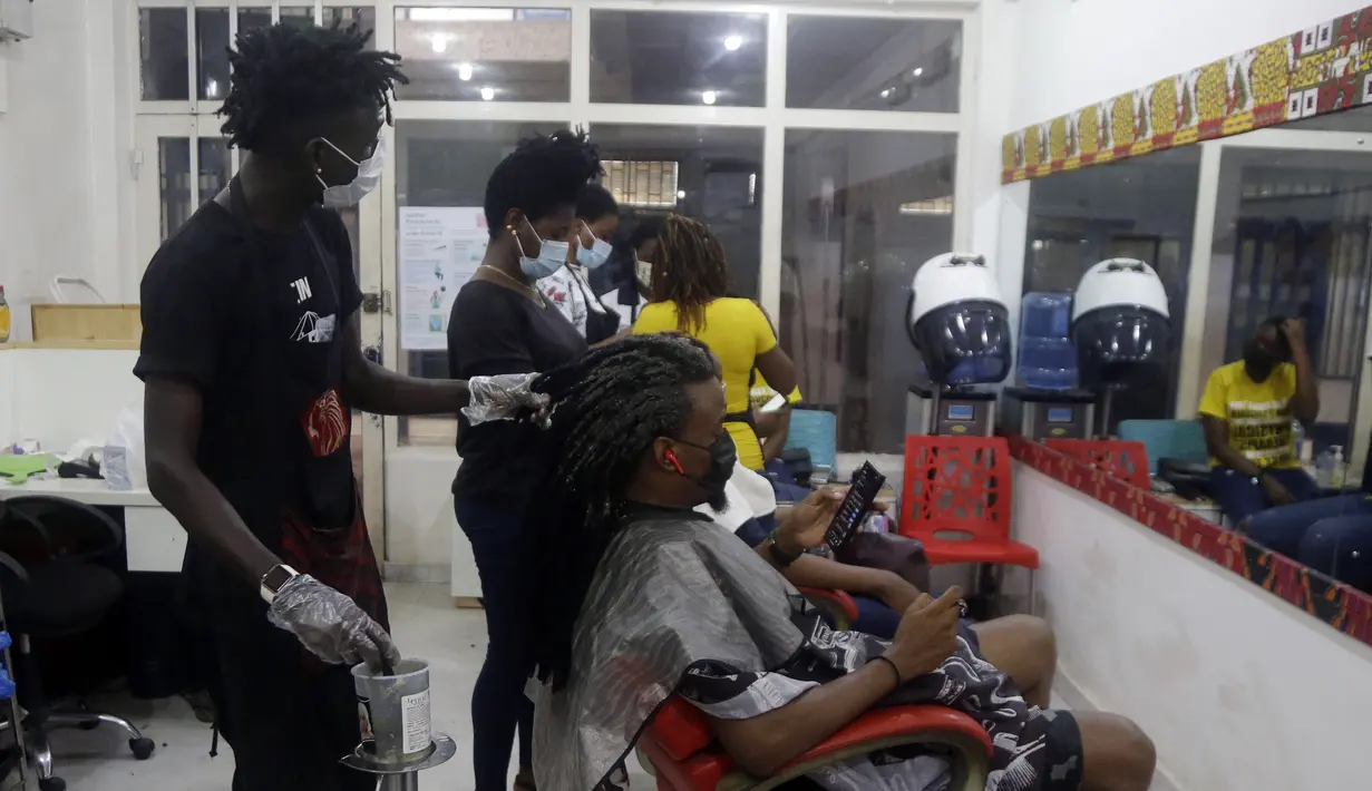 Penata rambut, memakai masker untuk melindungi dari virus corona, mengecat rambut pelanggan di dalam salon di Lagos, Nigeria, Rabu (26/5/2021). (AP Photo/Sunday Alamba)
