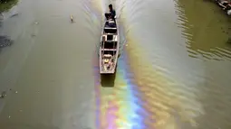 Seorang pria mengendarai perahu di sepanjang sungai yang tercemar oleh bahan bakar di Shaoxing, Zhejiang, Tiongkok pada 29 April 2015. Pertumbuhan industri dan kurangnya kesadaran lingkungan membuat saluran air terkontaminasi (REUTERS / Stringer)