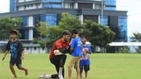 Kiper Arema, Adilson Maringa dengan sabar meladeni permintaan suporter kecil usai sesi latihan. (Iwan Setiawan/Bola.com)