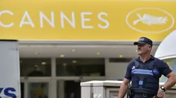 Seorang polisi Prancis berdiri di depan Festival Palace pada malam pembukaan Festival Film Cannes ke-69, Selasa (10/5). Ketatnya penjagaan dilakukan mengingat Prancis masih dalam kondisi waspada akibat berisiko tinggi terhadap serangan. (Loic VENANCE/AFP)