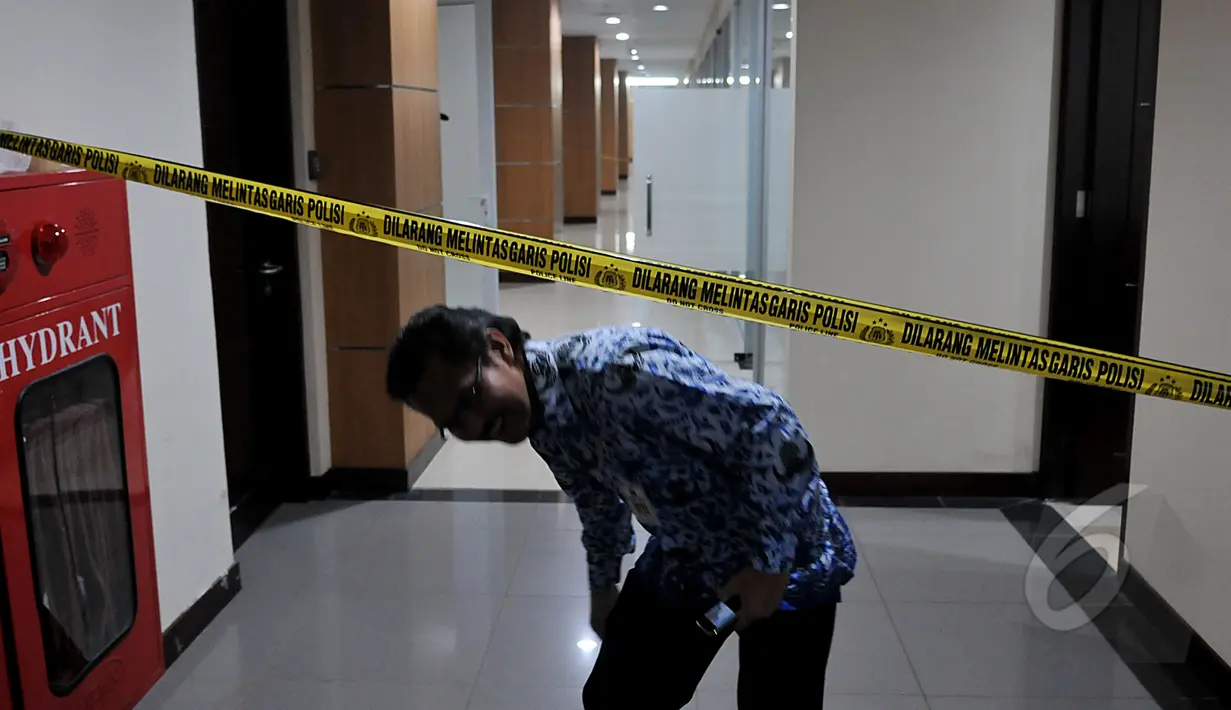 Seorang PNS melintasi garis polisi di depan ruang kerja Wakil Ketua DPRD DKI Jakarta Abraham Lunggana, Jakarta, Senin (27/4/2015). Pemeriksaan ruang kerja ini terkait kasus UPS.(Liputan6.com/JohanTallo)