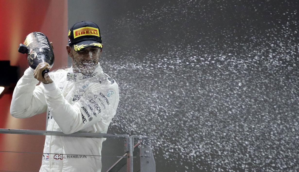 Pebalap Mercedes, Lewis Hamilton  menyemprotkan champagne saat menerima penghargaan di podium pada balapan F1 Singapura di Marina Bay City Circuit Singapore, (17/9/2017).  (AP/Wong Maye-E)