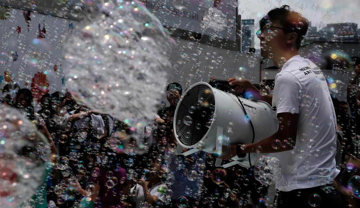 Seorang petugas meniupkan angin pada gelembung selama pertunjukan seni Bubble Up yang dibuat oleh seniman asal Jepang Shinji Ohmaki, di Hong Kong, 2 Agustus 2017. (AP Photo/Kin Cheung)