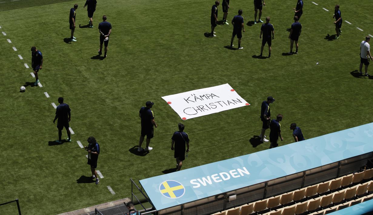 Tim Swedia berpose di sebelah tanda bertuliskan "Get Well Christian" untuk gelandang Denmark Christian Eriksen selama sesi latihan di stadion La Cartuja di Seville, Spanyol, Minggu (13/6/2021). Eriksen pingsan di lapangan saat melawan Finlandia pada grup B Euro 2020. (Julio Munoz/Pool via AP)