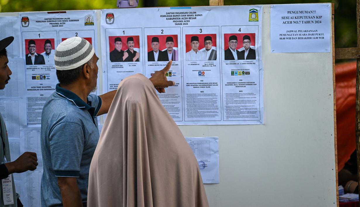 Melalui Pilkada, para pemimpin daerah yang dipilih langsung oleh rakyat diharapkan bekerja lebih maksimal dalam menjalankan tugas dan meningkatkan kesejahteraan masyarakat. Tampak dalam foto, calon pemilih memeriksa kandidat sebelum memberikan suara mereka dalam pemilihan eksekutif lokal di Darul Imarah, pinggiran Banda Aceh pada 27 November 2024. (CHAIDEER MAHYUDDIN/AFP)