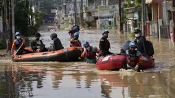 Warga duduk dalam perahu karet saat mereka mengungsi ke tempat yang lebih tinggi selama banjir di Bekasi, Jawa Barat, Kamis (17/2/2022). Hujan deras yang dikombinasikan dengan perencanaan pembuangan limbah kota yang buruk sering menyebabkan banjir besar. (AP Photo/Achmad Ibrahim)