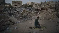 Seorang pria Palestina berdoa di samping puing-puing rumah keluarganya yang hancur karena serangan udara Israel di Beit Lahia, Jalur Gaza, Jumat (4/6/2021). Gencatan senjata yang mengakhiri perang 11 hari antara Hamas dan Israel telah lama dilakukan. (AP Photo/Felipe Dana)