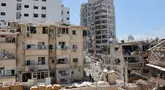 Petugas tanggap darurat Israel berdiri di antara puing-puing bangunan yang rusak berat, setelah serangan rudal Iran semalam di Bat Yam pada 15 Juni 2025. (GIL COHEN-MAGEN/AFP)