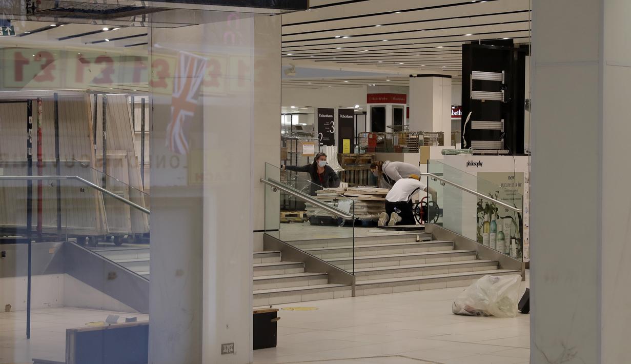 Para pekerja terlihat dari jendela pintu masuk sedang mengemas di dalam department store Debenhams yang tutup di Oxford Street di London, Sabtu (6/2/2021). Pengecer mode online, Boohoo telah membeli merek dan situs web Debenhams seharga 55 juta pound (sekitar Rp 1 triliun). (AP Photo/Matt Dunham)