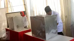 Calon Walikota Tangerang Selatan nomor urut 2 Arsid beserta istri mencoblos surat suara di bilik saat menggunakan hak pilihnya di TPS 31 Kelurahan Pondok Benda, Tangsel, Rabu (9/12). (Liputan6.com/Fery Pradolo)