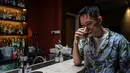 Seorang karyawan berpose sambil menikmati segelas minuman Pfizermeister, minuman yang terinspirasi oleh vaksin virus corona Covid-19, di sebuah bar koktail di George Town di pulau Penang, Malaysia (8/9/2021). (AFP/Mohd Rasfan)