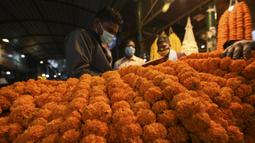 Karangan bunga dipajang pada sebuah toko jelang Festival Diwali di pasar bunga New Delhi, India, Minggu (31/10/2021). Festival Diwali atau Festival Cahaya dalam agama Hindu melambangkan kemenangan baik atas buruk. (Money SHARMA/AFP)
