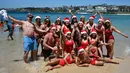Sejumlah turis berpose mengenakan topi Santa di Pantai Bondi selama  Hari Natal 2018, Australia (25/12). (AFP Photo/Peter Parks)