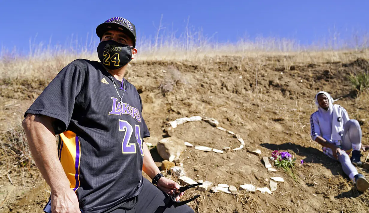Eric Dominguez (kiri) dan Dontate Matthews mengunjungi lokasi kecelakaan helikopter yang menewaskan Bryant, putrinya Gianna, dan tujuh orang lainnya satu tahun lalu di Calabasas, California, Amerika Serikat, Selasa (26/1/2021). (AP Photo/Marcio Jose Sanchez)