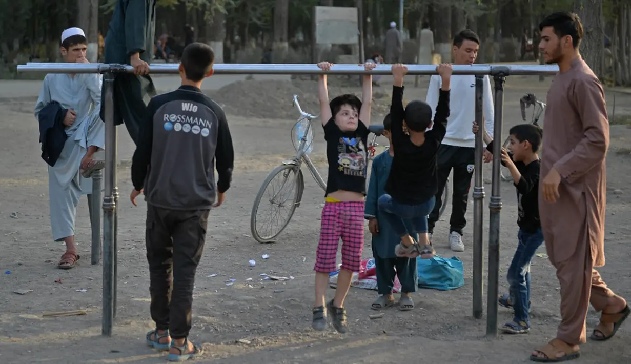 Anak-anak bermain pada palang besi yang terpasang di Shahr-e Naw Park, Kabul, Afghanistan, 9 September 2021. Taliban menguasai Afghanistan setelah pasukan Amerika Serikat meninggalkan negara tersebut. (HOSHANG HASHIMI/AFP)