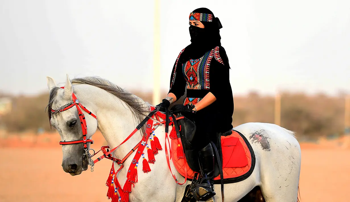 Perempuan Arab berpose saat menunggangi kuda dalam Festival Souk Okaz 2019 di Kota Taif, Arab Saudi, Rabu (7/8/2019). Perempuan penunggang kuda dari berbagai negara Arab ambil bagian dalam Festival Souq Okaz 2019. (AMER HILABI/AFP)