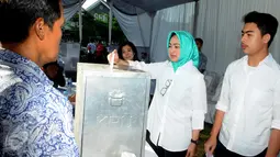 Calon Walikota Tangerang Selatan, Airin Rachmi Diany (kiri) bersama putra pertama, TB Ghifari Wardana memasukkan surat suara ke kotak suara di TPS 17 Serpong Utara, Tangerang Selatan, Banten, Rabu (9/12). (Liputan6.com/Helmi Afandi)